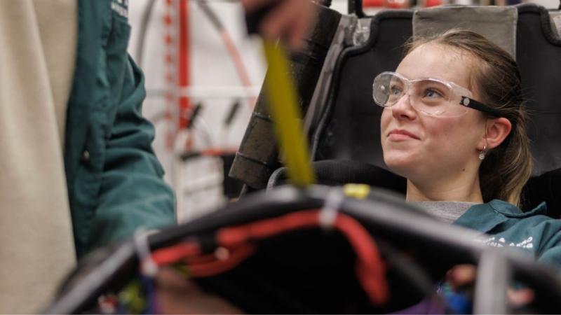 female student with protective goggles on in a workshop environment